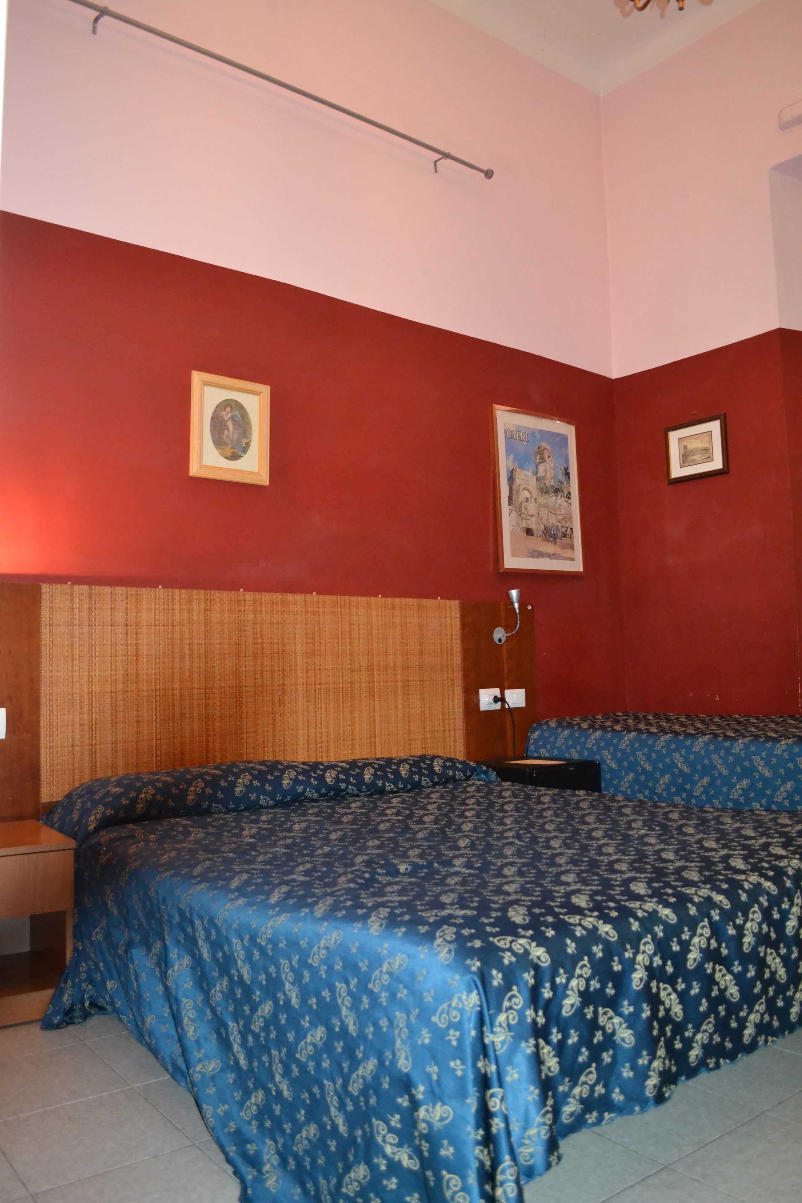 A room with a bed, a wooden headboard, and two framed pictures on the wall.
