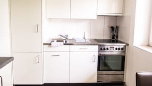 Een moderne keuken met witte kasten, een roestvrijstalen spoelbak, een kookplaat en een oven.