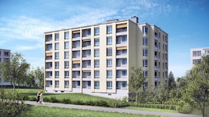Een meerlaags woongebouw met balkons, omgeven door groen en een heldere lucht.