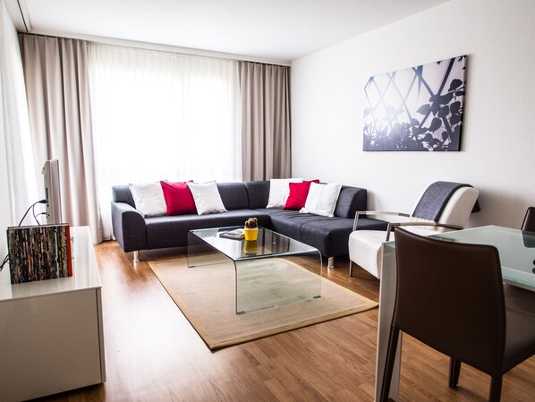 A modern living room with a sofa, coffee table, and a dining area.