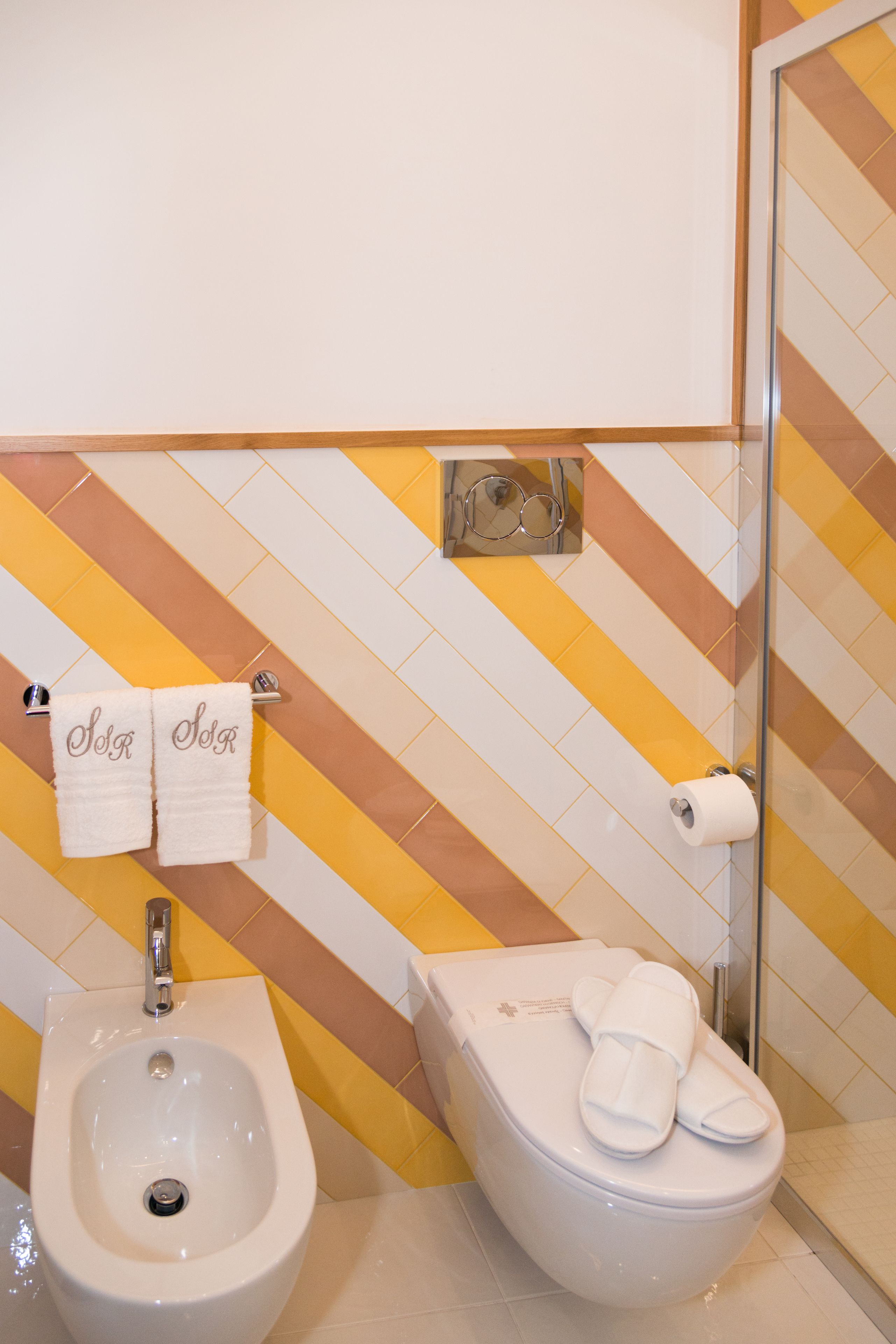 Un bany amb bidet, vàter i un suport de tovalloles amb tovalloles.