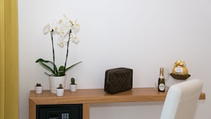 Una estantería de madera con una orquídea en maceta, un pequeño cactus, un bolso Louis Vuitton, una botella de champán y una copa.