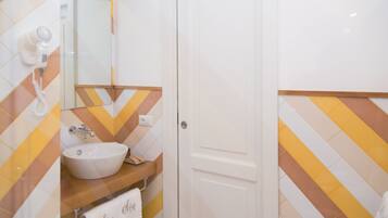 A bathroom with a white sink, mirror, and towel rack. The walls have a chevron pattern in yellow and white.