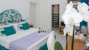 Un dormitorio con una cama, una mesita de noche, un aparador y una orquídea en maceta.