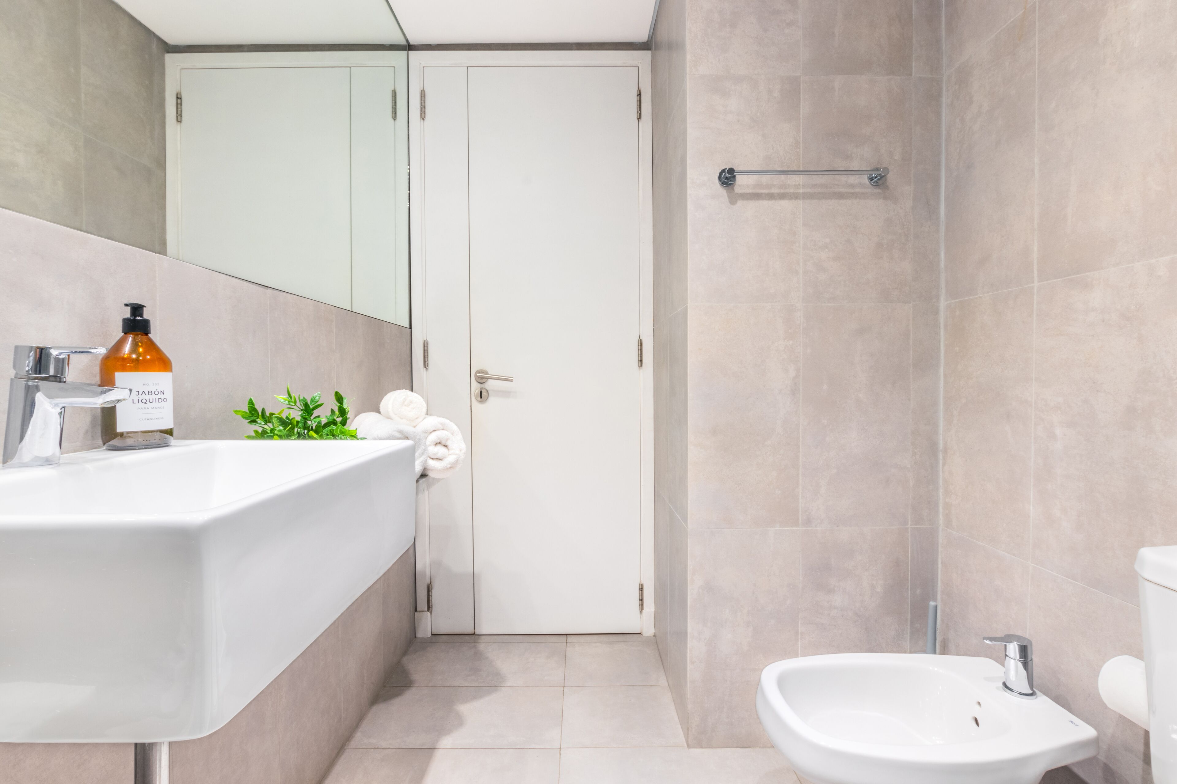A modern bathroom with a white sink, a bidet, and a shower area.