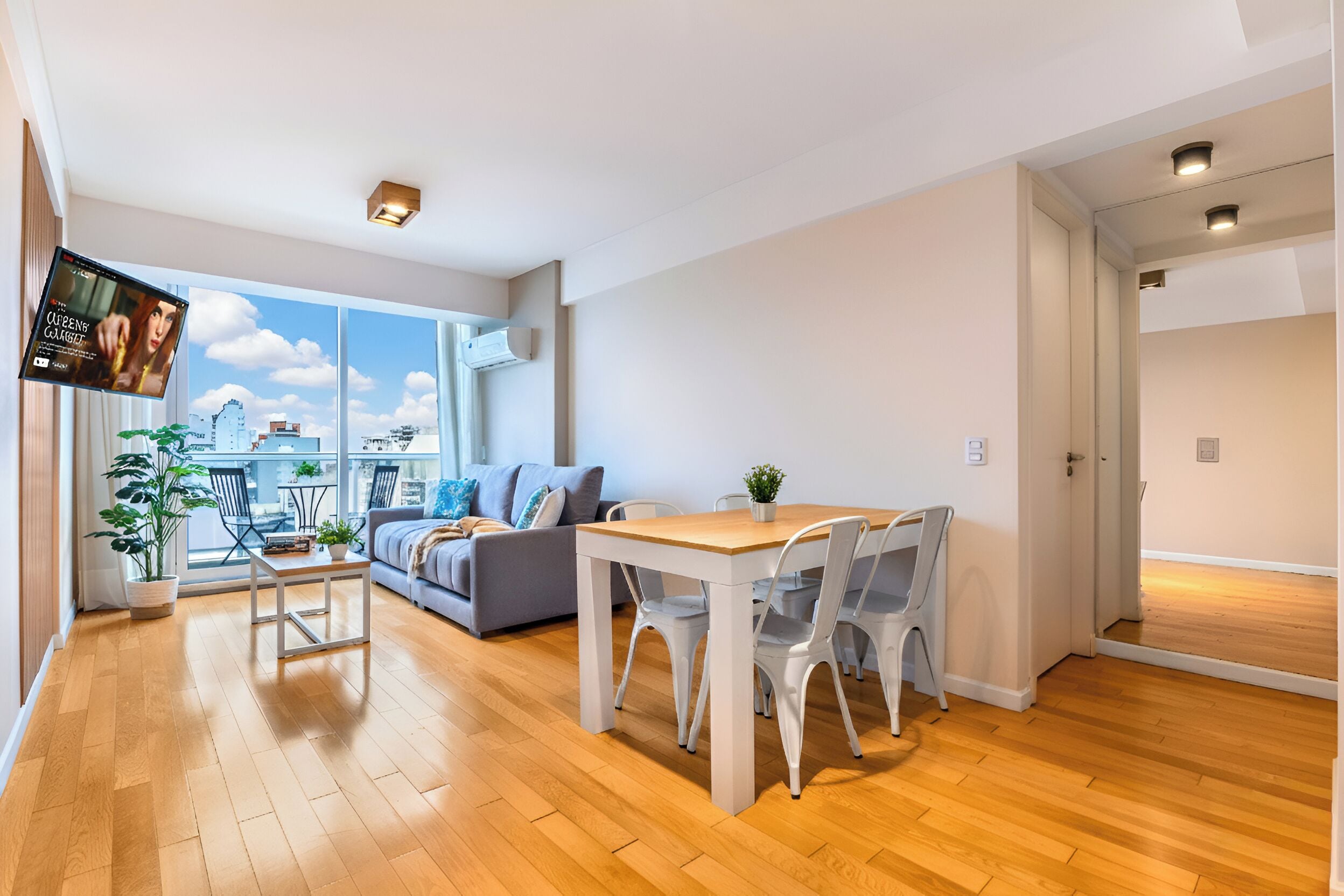 Un appartement moderne comprenant un coin repas, un canapé et un téléviseur diffusant un film.