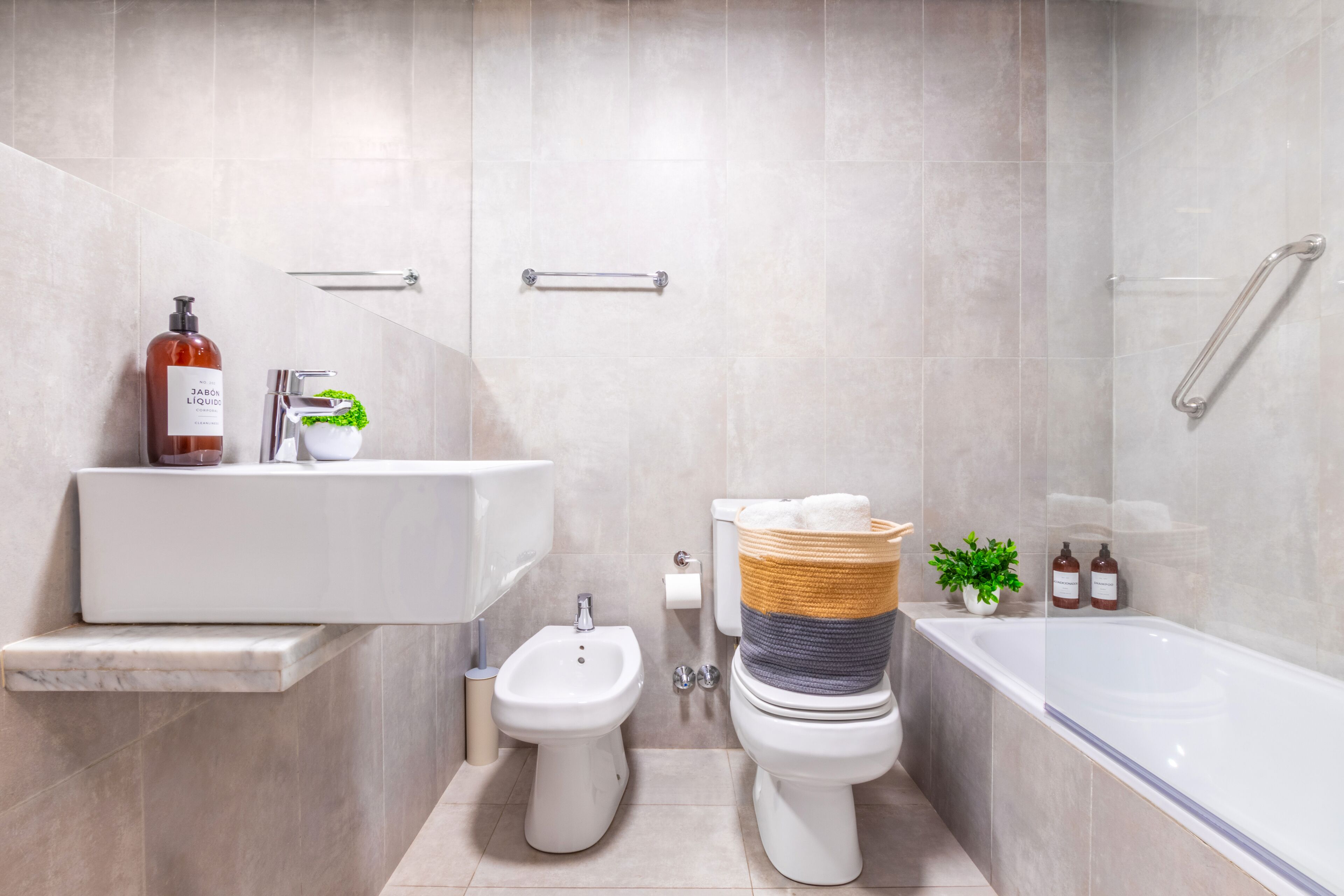 Un baño moderno con bidé, inodoro, lavamanos y bañera.