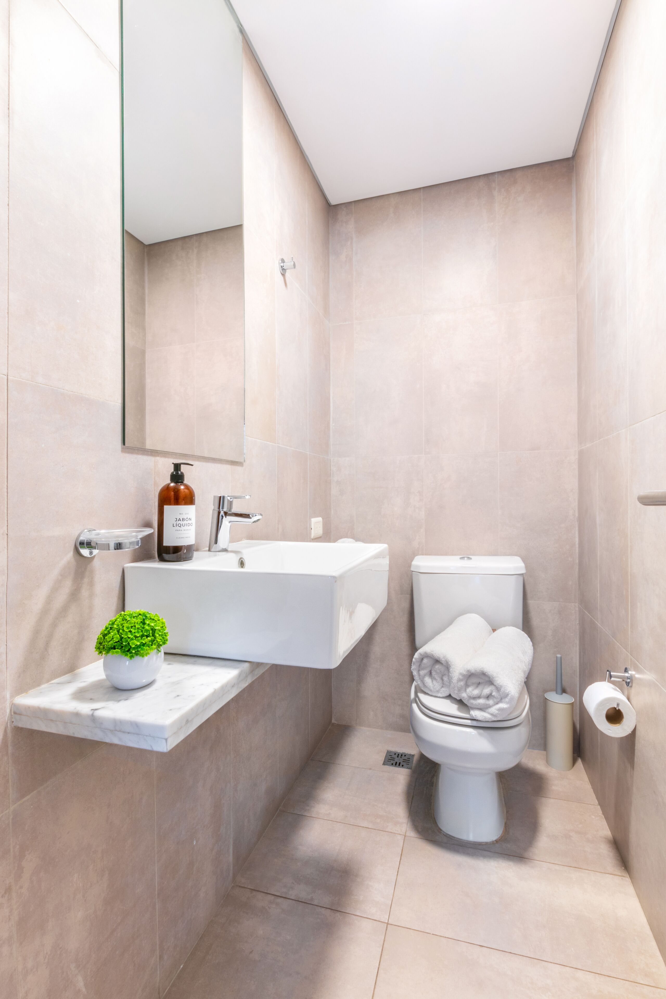 Un baño moderno con un lavamanos blanco, un inodoro y un espejo.
