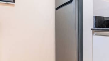 A kitchen with a stainless steel refrigerator, a wall clock, and a built-in oven.