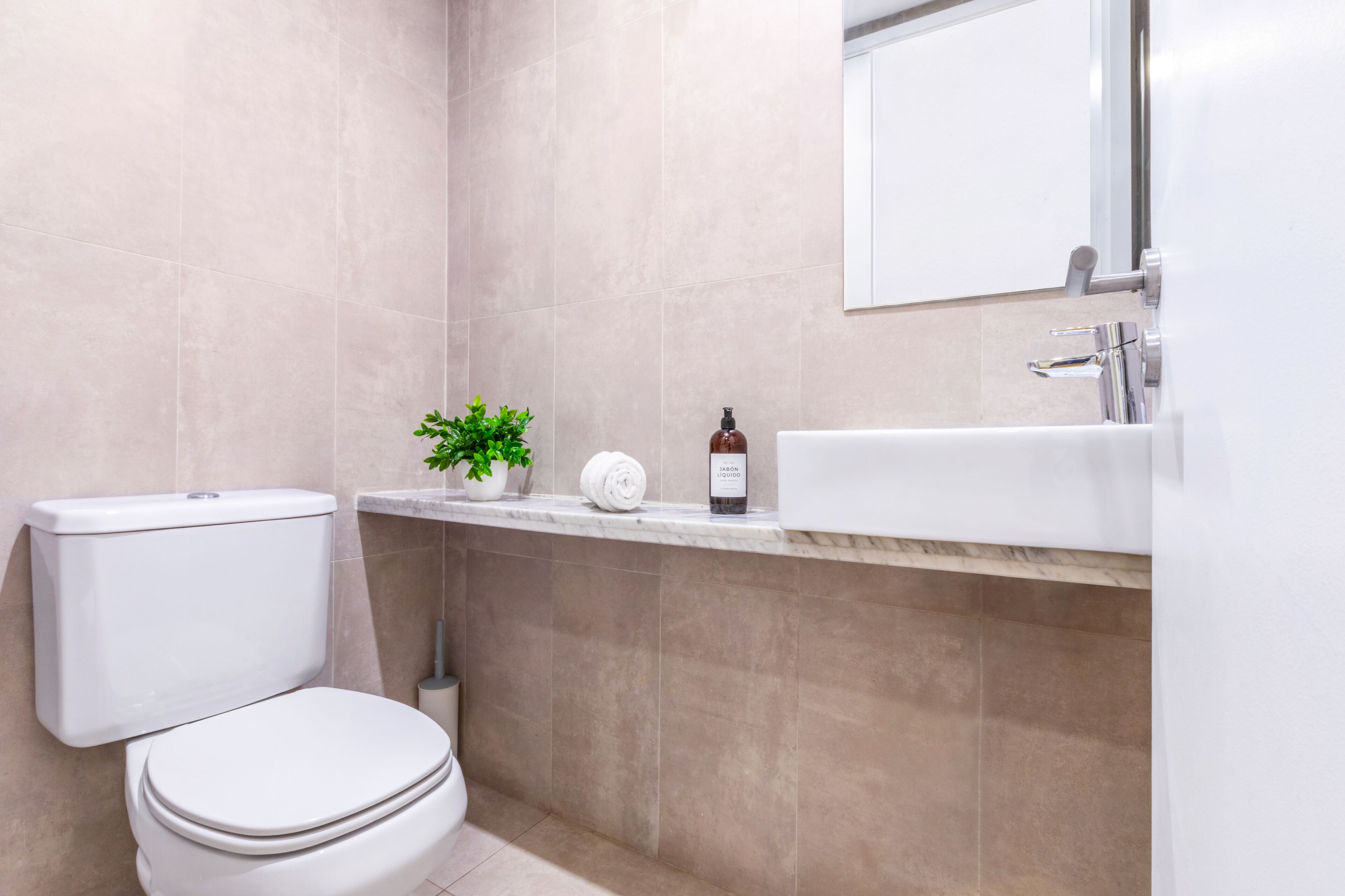 A modern bathroom with a toilet, a sink, and a mirror.