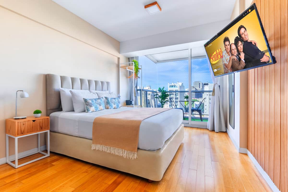 A modern bedroom with a large bed, a bedside table, and a view of the city through large windows.