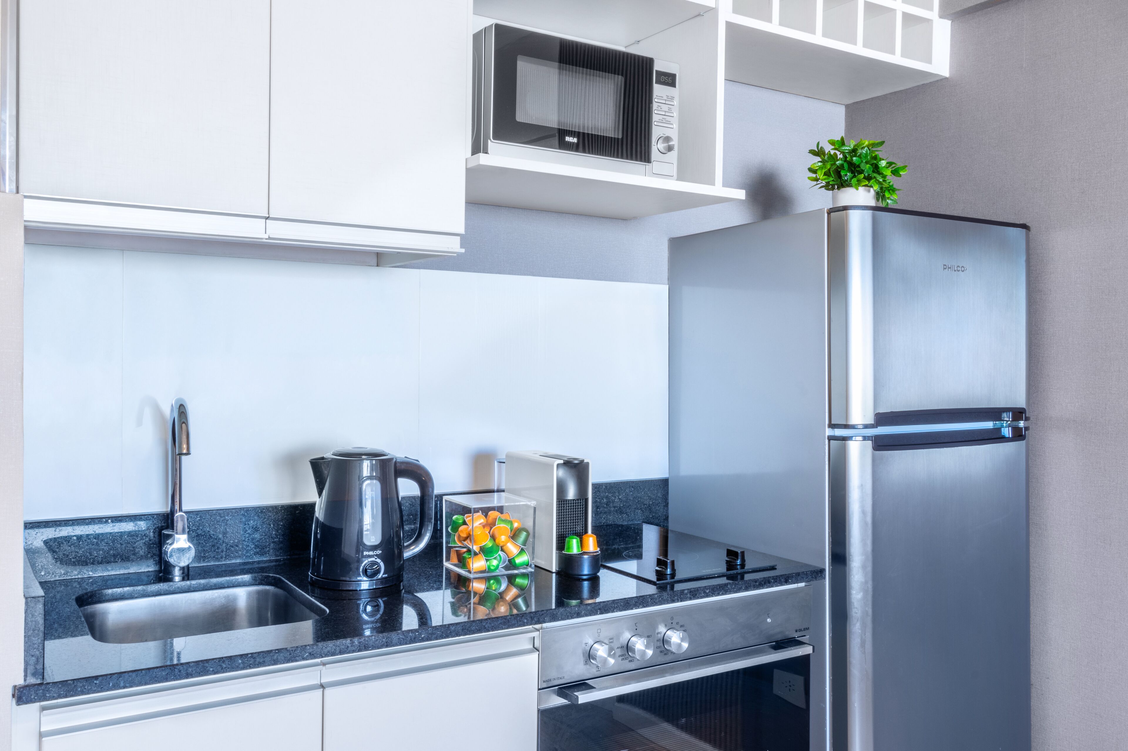 A modern kitchen with a stainless steel refrigerator, a microwave, a kettle, and a coffee maker on the counter.