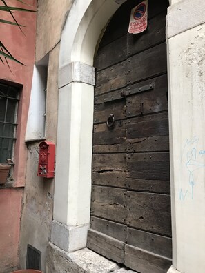 A weathered wooden door with a metal latch, a red mailbox, and a sign prohibiting dogs. - Suites Imperiali Guest House (Rome)