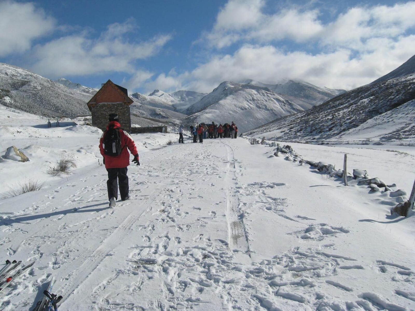 Un sendero cubierto de nieve que conduce a una montaña con una construcción de piedra.