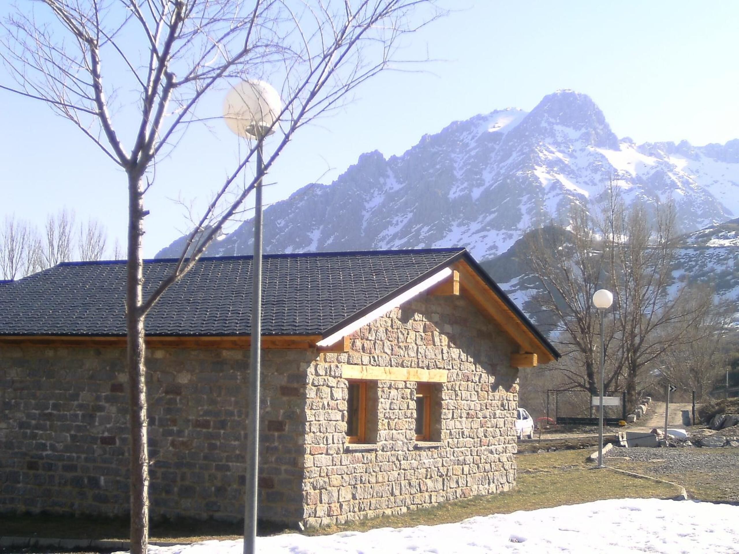 A stone building with a sloped roof, a small window, and a wooden beam structure.