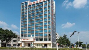 Un hotel de varios pisos con fachada moderna, que destaca por su entrada principal y una serie de ventanas.