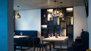 Een moderne eethoek met een houten tafel, zwarte stoelen en een blauwe bank.