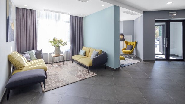Een moderne woonkamer met een bank, fauteuil en een bijzettafeltje met een plant.