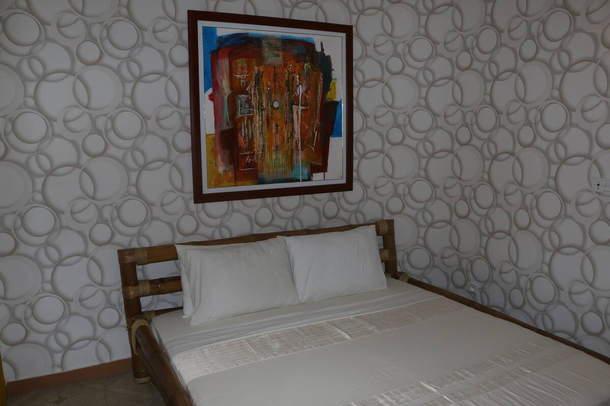 Une chambre d’hôtel avec un lit, une tête de lit en bois et un mur orné de motifs circulaires.