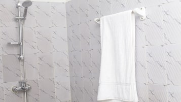 A bathroom with a shower, tiled walls, and a towel rack.