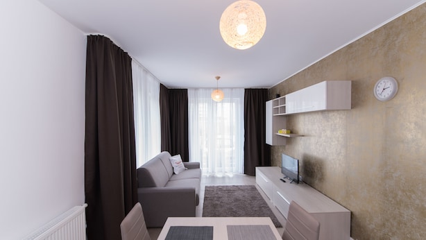 A modern living room with a sofa, a coffee table, a TV, and a wall-mounted shelf. - Thomas Apartments (Brasov)