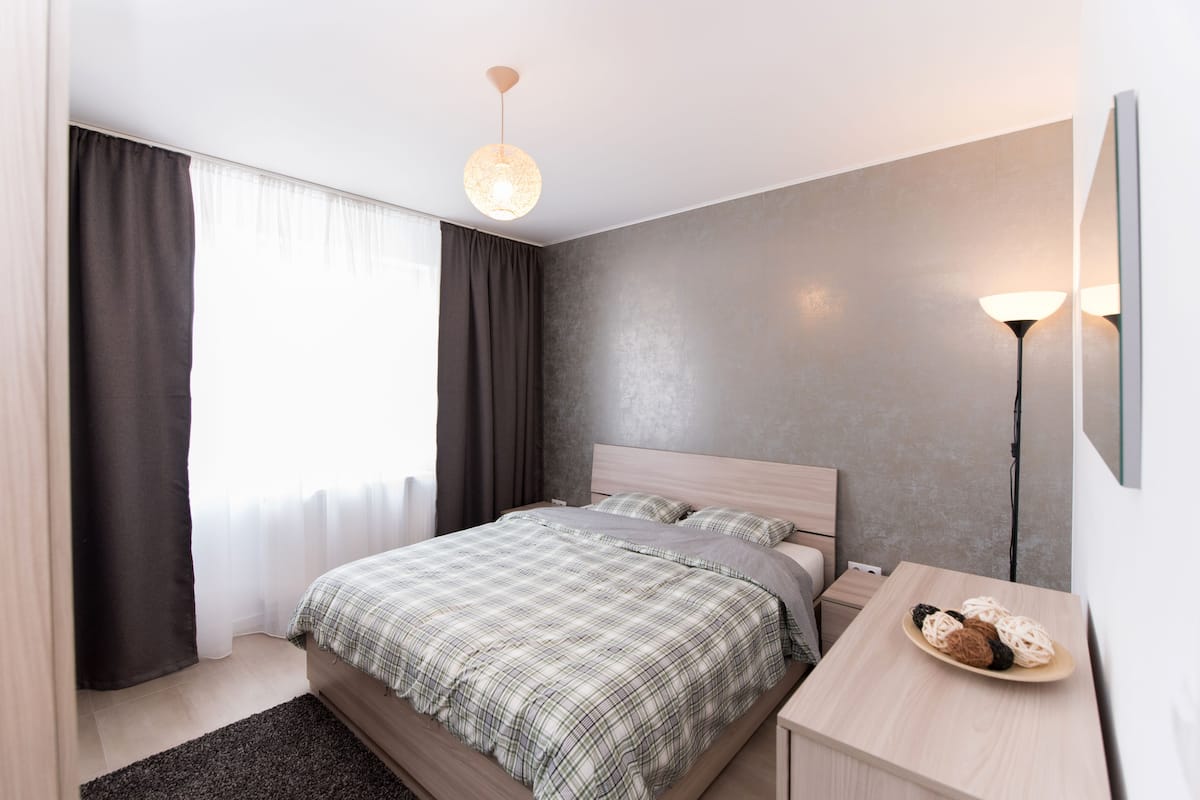 A modern bedroom with a bed, bedside table, and a lamp.