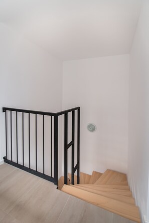 A staircase with a black metal railing and wooden steps. - Thomas Apartments (Brasov)