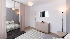 A modern bedroom with a bed, dresser, and a mirror. - Thomas Apartments (Brasov)