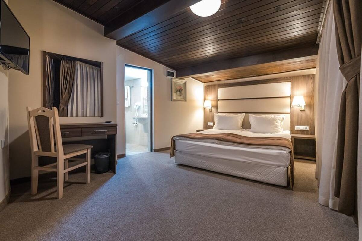 Un dormitorio con cama, mesitas de noche, escritorio y silla.