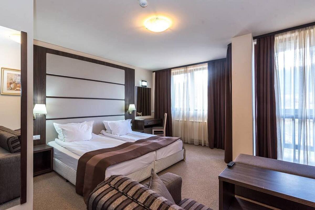Una habitación de hotel con una cama grande, una mesita de noche, una silla y un escritorio.