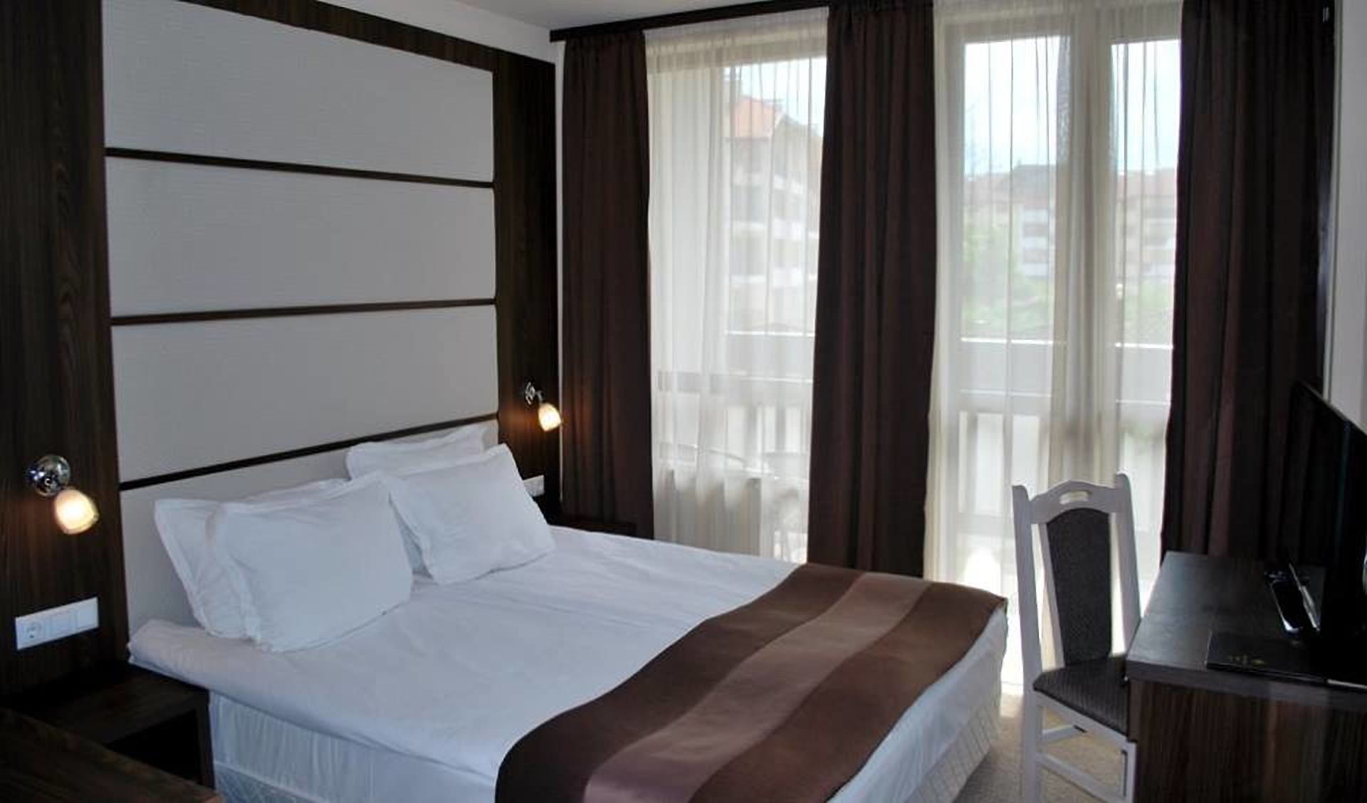 A hotel room with a bed, a desk, and a chair.