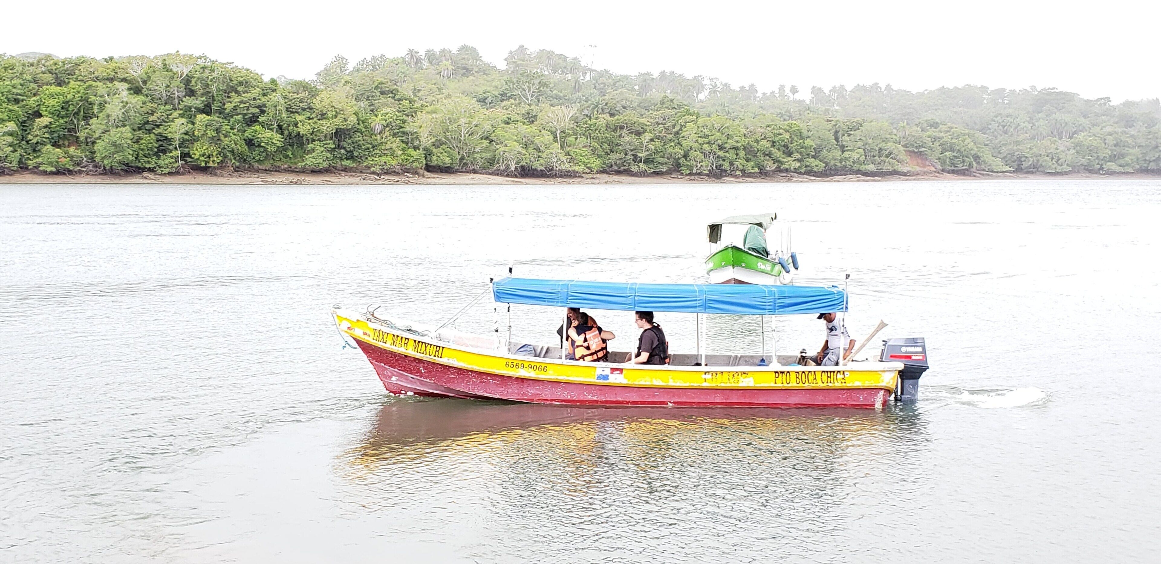 Una embarcación con pasajeros navegando por un río tranquilo.