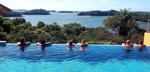 A swimming pool with a view of the sea and surrounding greenery.