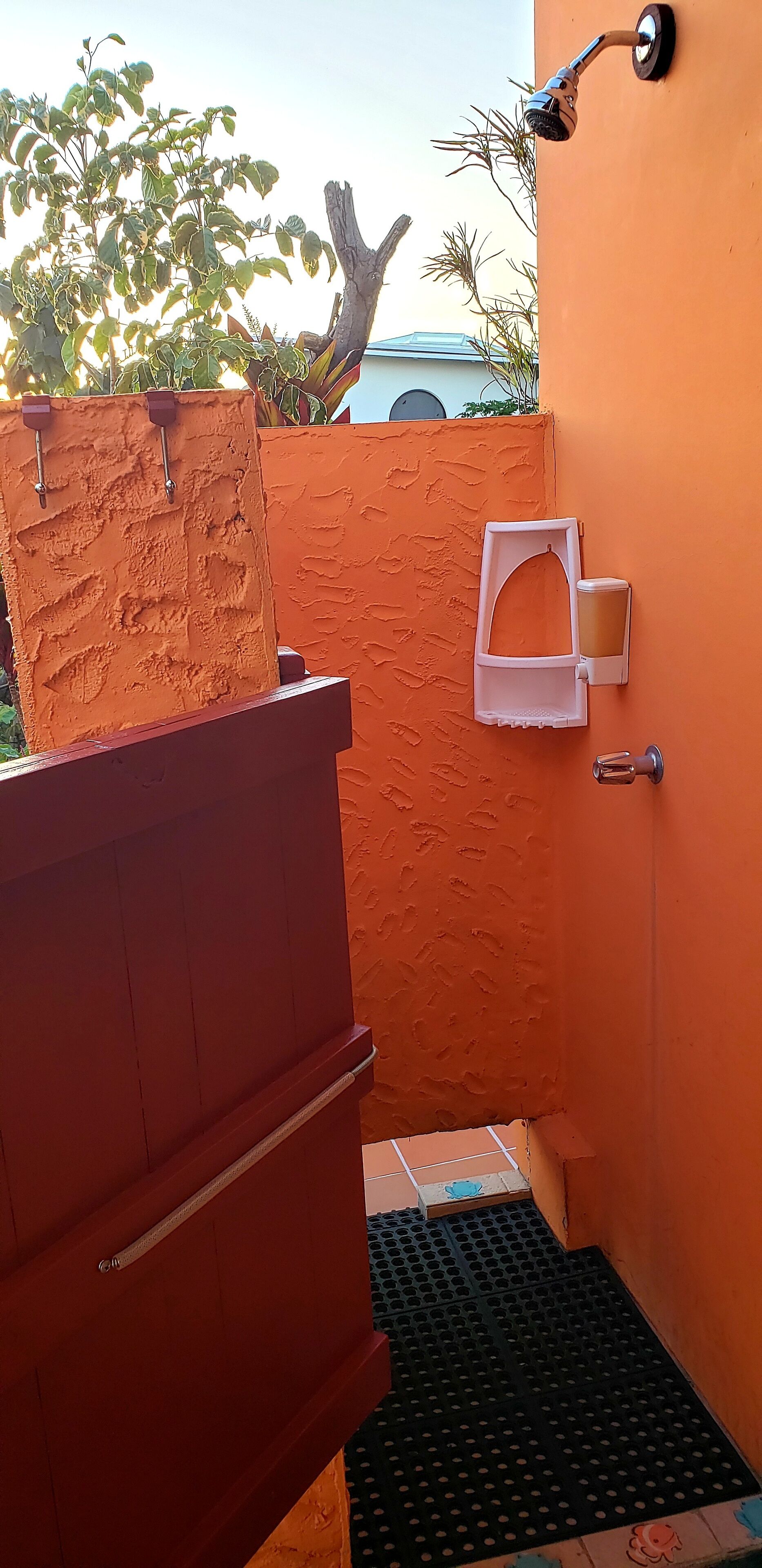A small, enclosed bathroom with a shower, a soap dispenser, and a door with a handle.