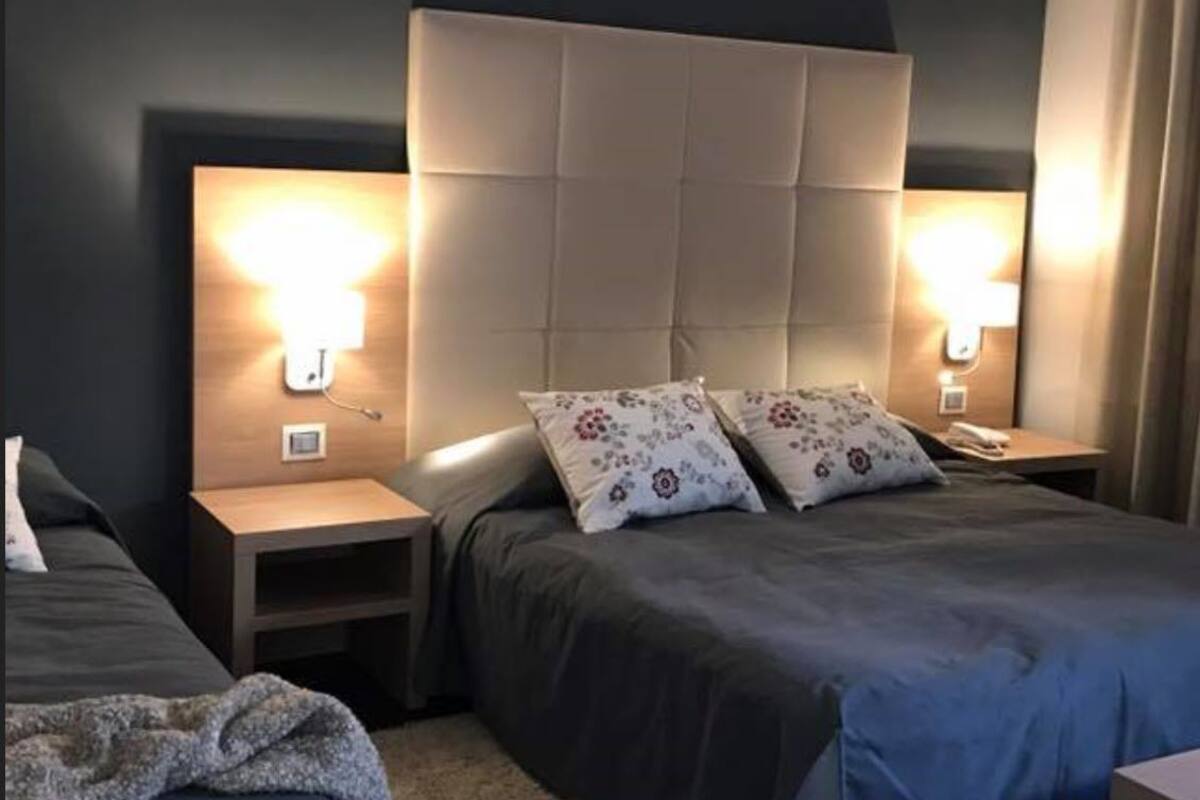 Ein Schlafzimmer mit einem großen Bett, zwei Nachttischen und zwei Wandlampen.