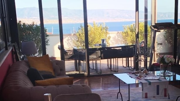 Un salon moderne doté d’une grande fenêtre, d’un canapé, d’une table basse et d’un coin repas.