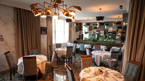A restaurant with multiple tables, chairs, and a large mirror on the wall. - Berwick Manor Hotel (Rainham)
