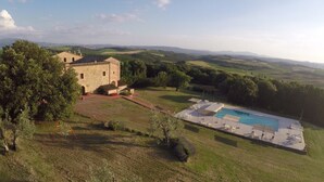 Un edificio de piedra con piscina y vistas a colinas onduladas.