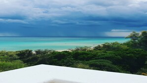 Une vue sur la plage avec une structure blanche au premier plan, un ciel dégagé et une mer calme.
