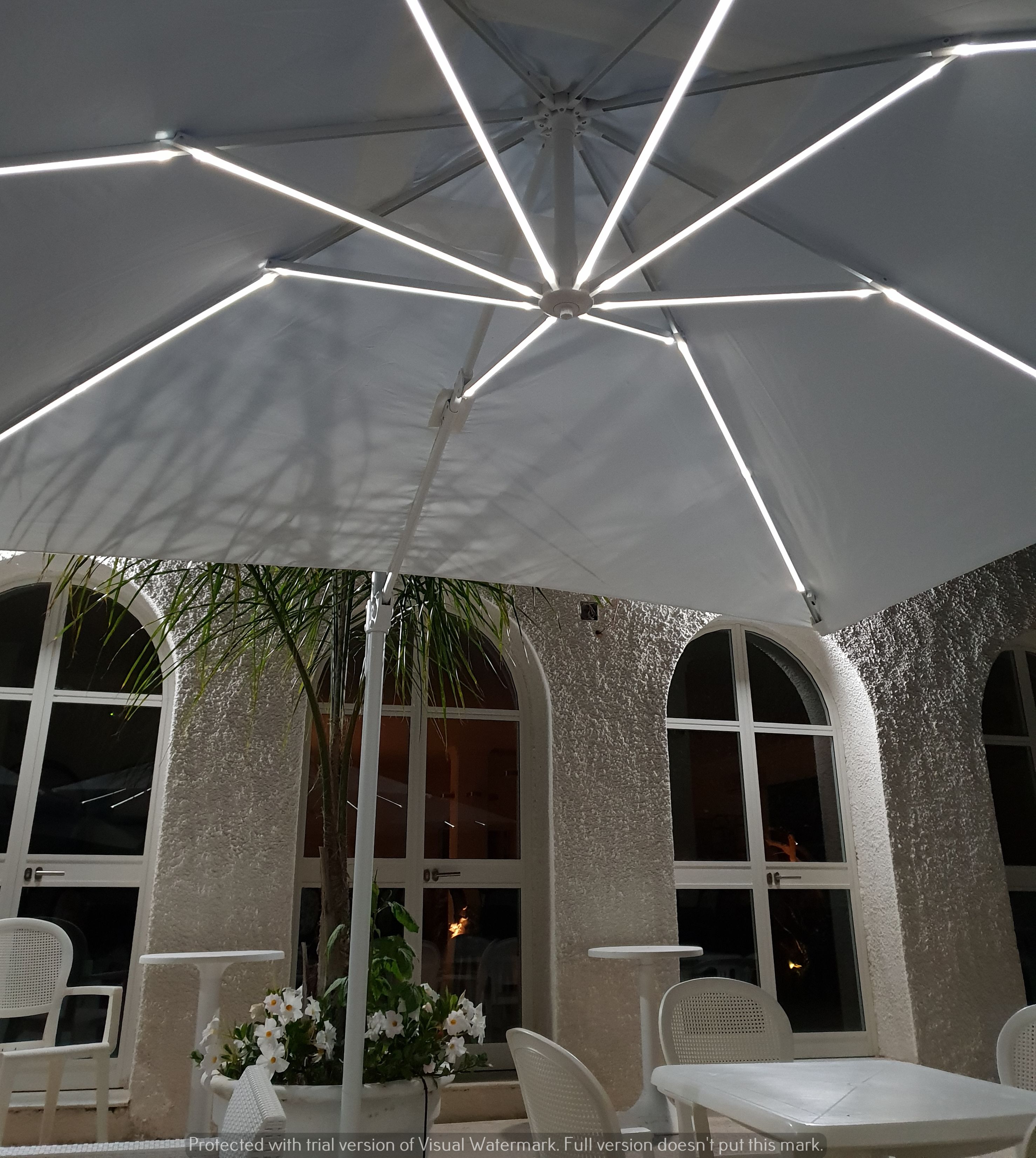 Zona patio esterna con un ombrellone bianco, sedie bianche e un tavolo.