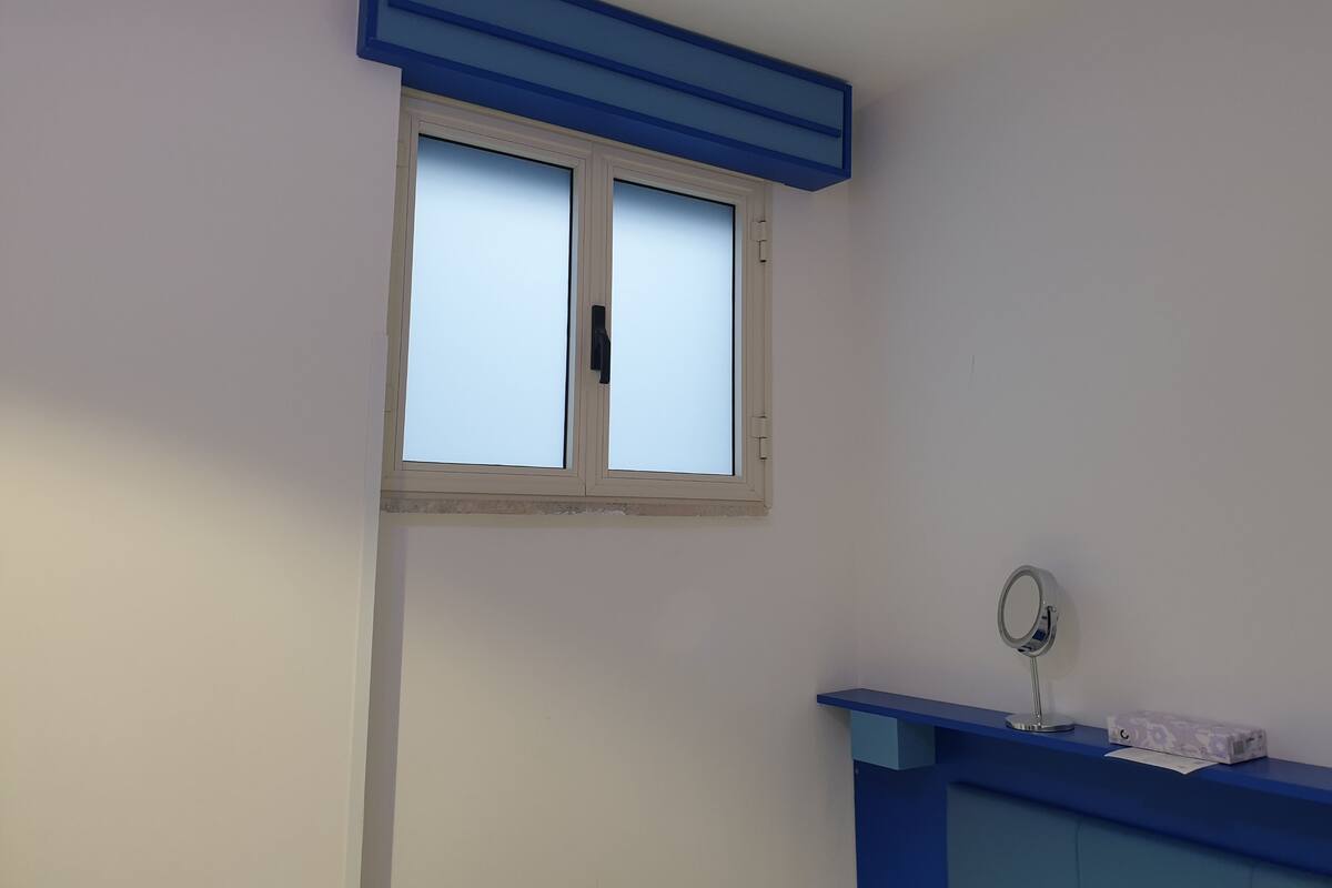 A bathroom with a window, a mirror, and a blue vanity.