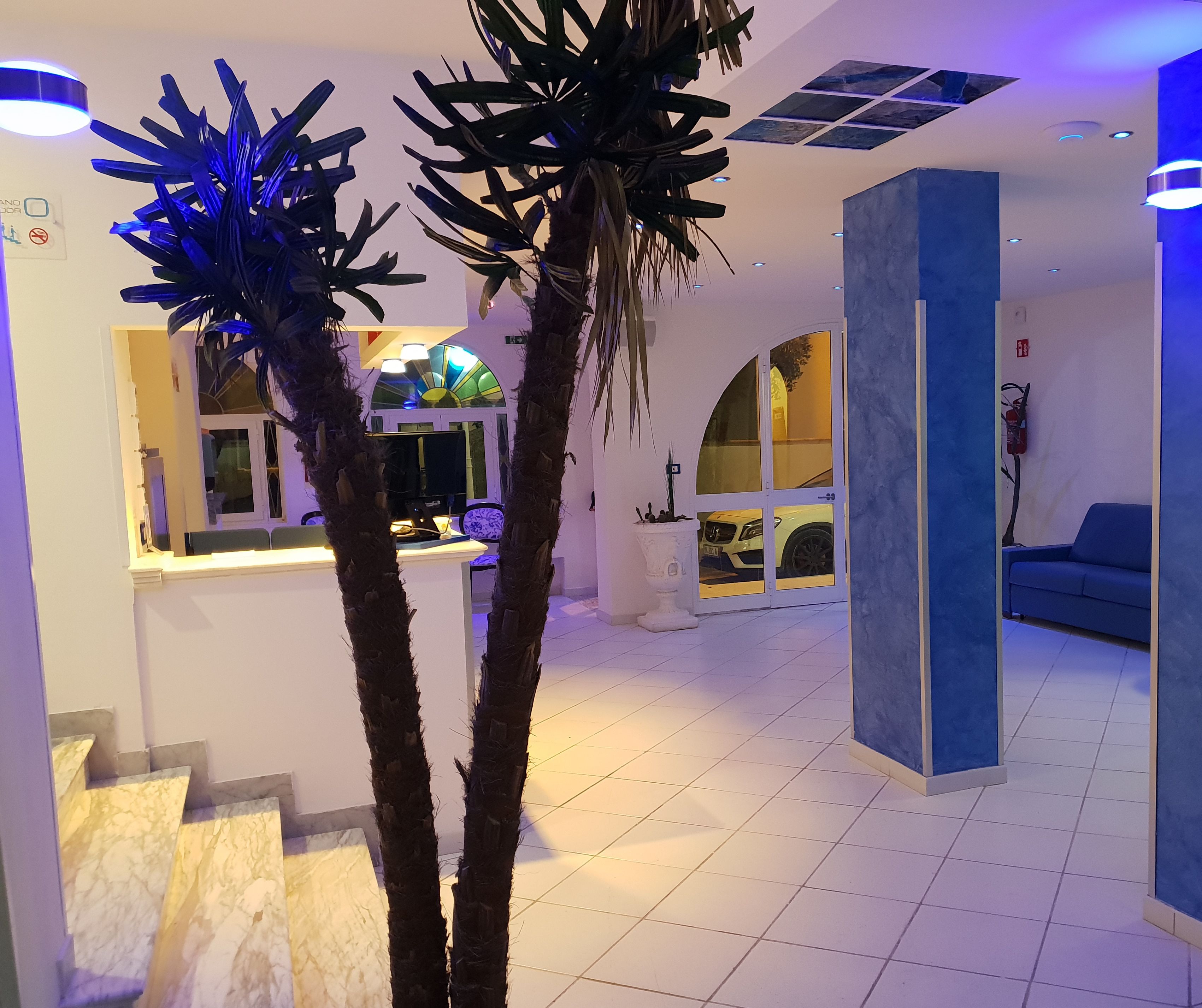 A modern interior with a reception desk, a blue sofa, and a staircase with marble steps.