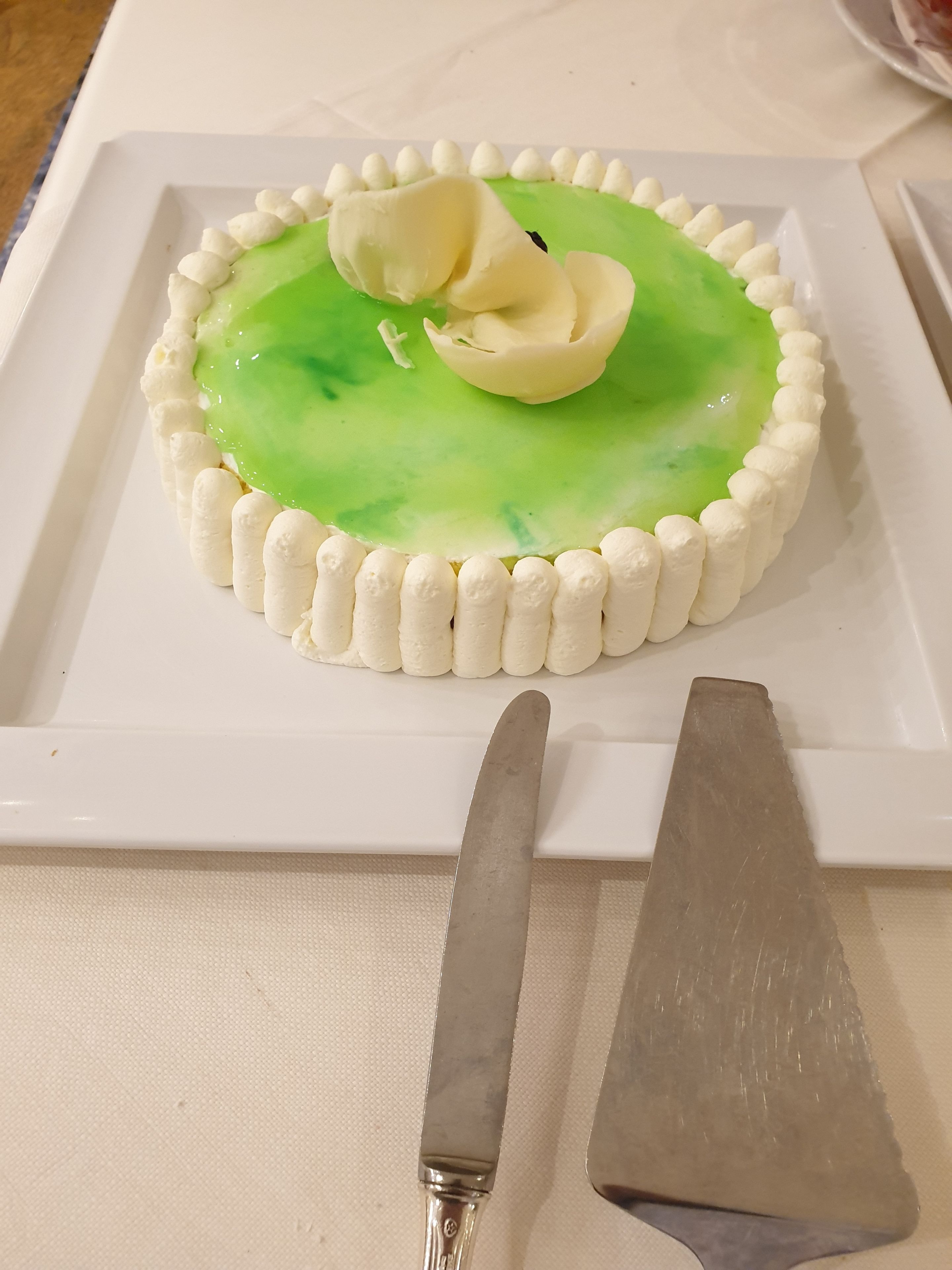 Un dessert servi dans une assiette blanche, avec un couteau et une spatule à côté.