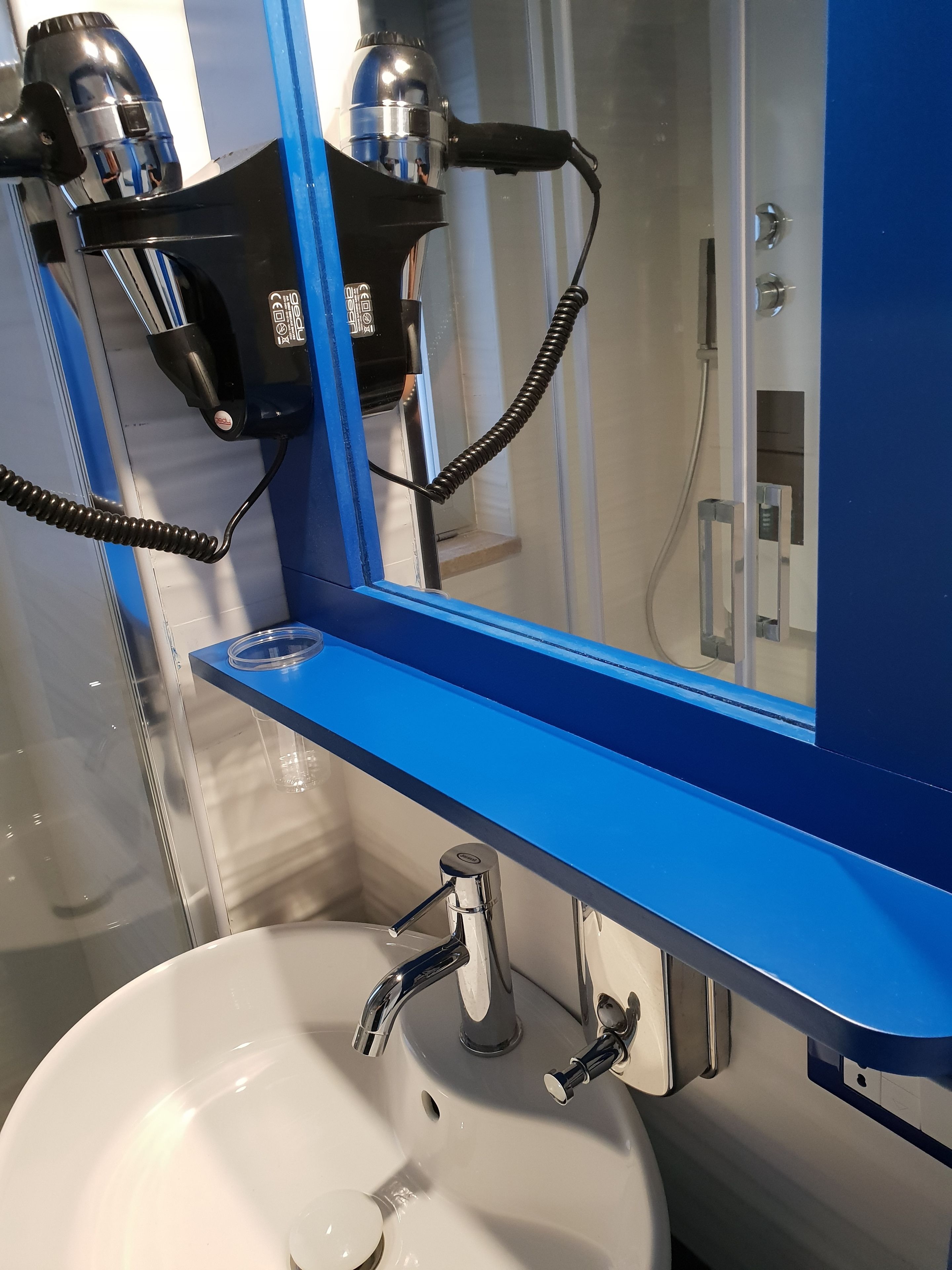 A bathroom with a white sink, a blue countertop, and a mirror.