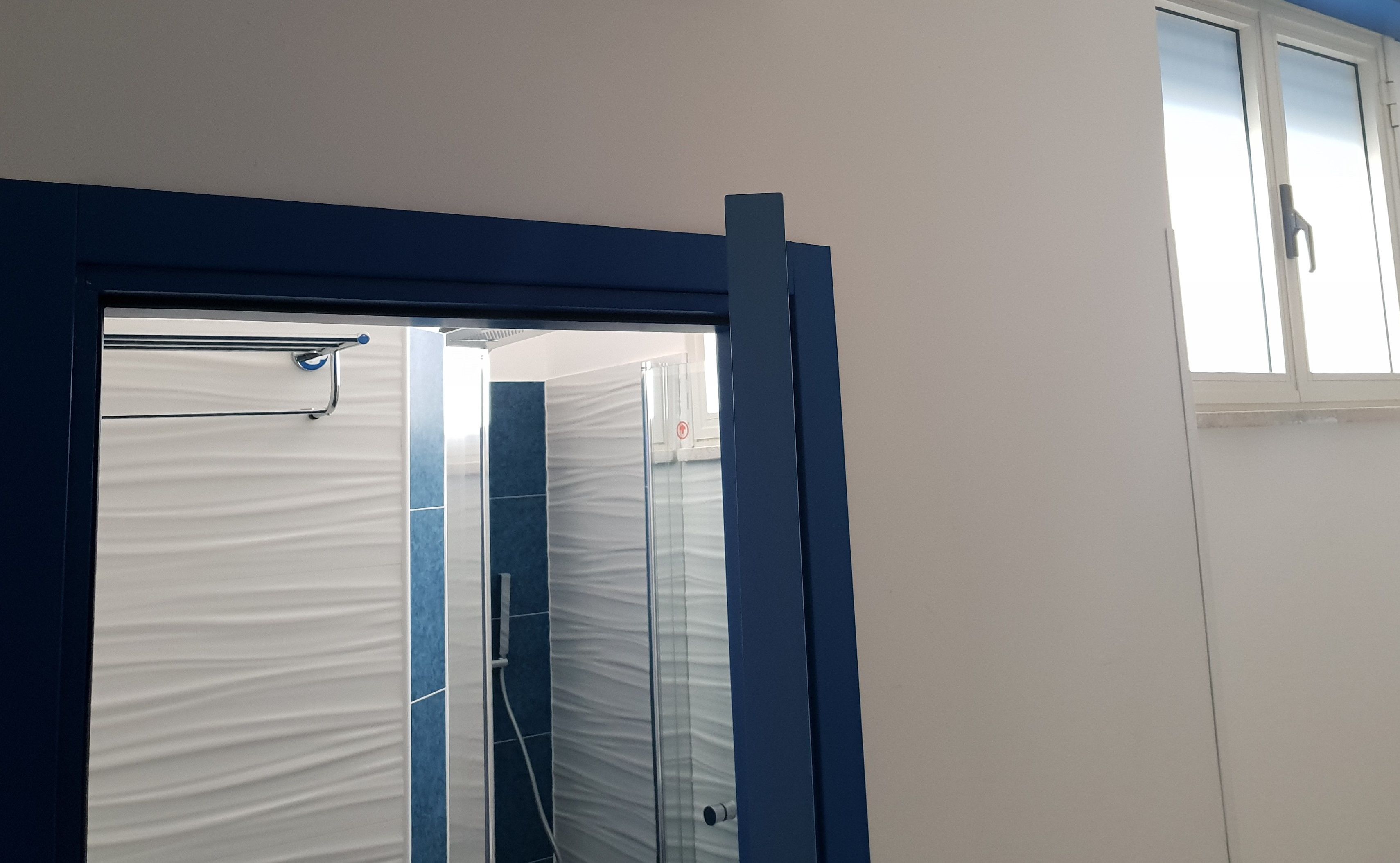 A bathroom with a shower, a towel rack, and a window.