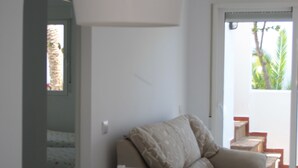A modern interior with a white sofa, a hanging light fixture, and a staircase leading to an outdoor area. - Apartamentos Torrelaguna (Vera)