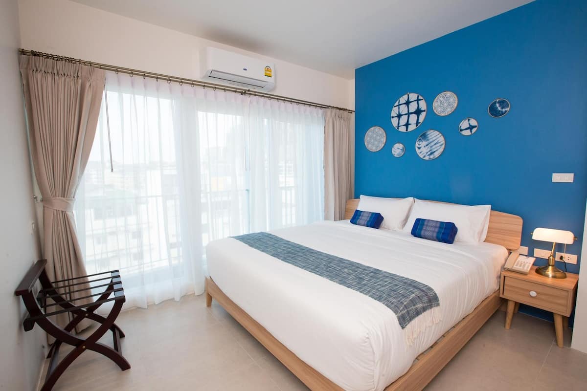 A bedroom with a large bed, a nightstand, a chair, and a blue accent wall with decorative plates.