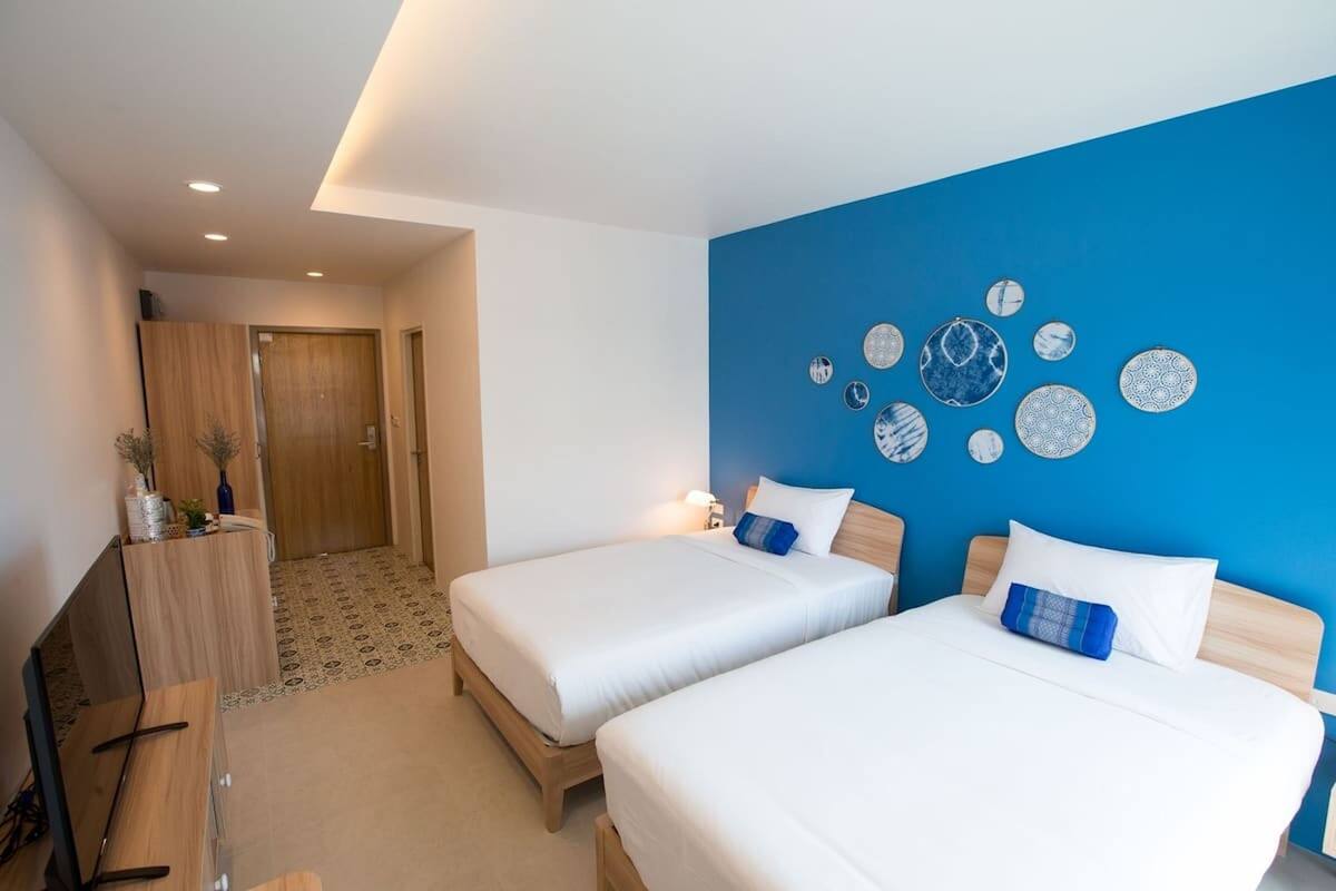 A hotel room with two beds, a desk, and a wall decorated with circular plates.