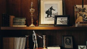 A wooden shelf with books, framed photographs, a candle, and a small wooden horse figurine.