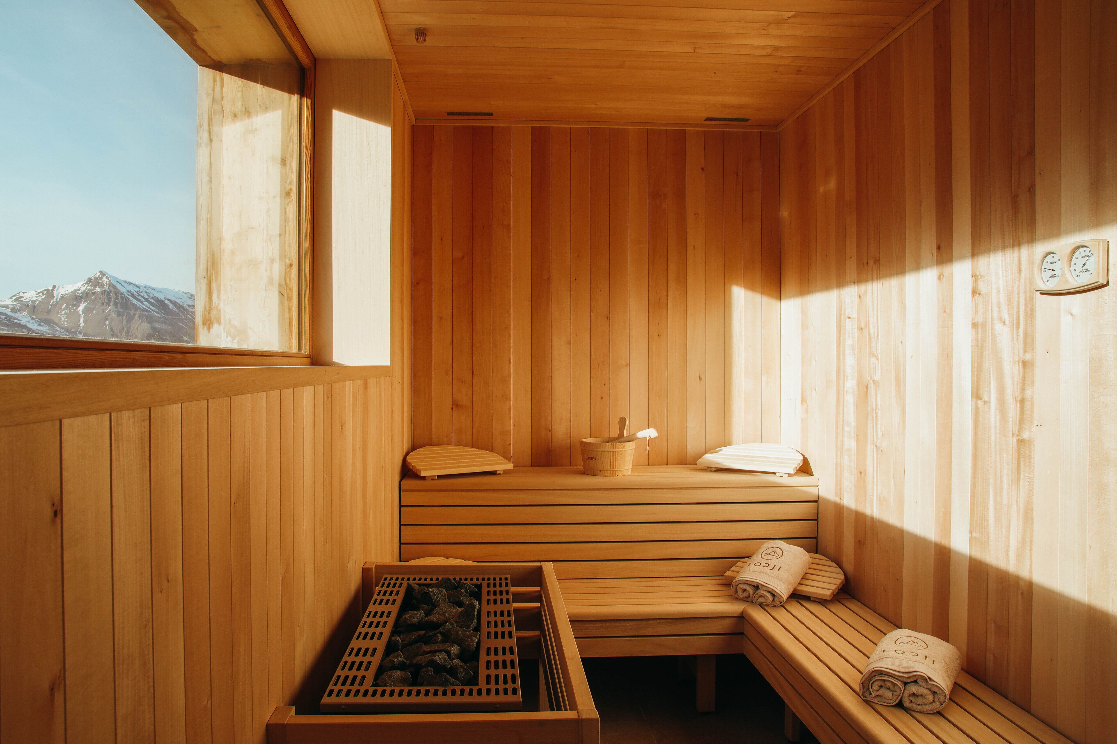 A wooden sauna with benches, a bench with towels, and a wooden tray with a towel.